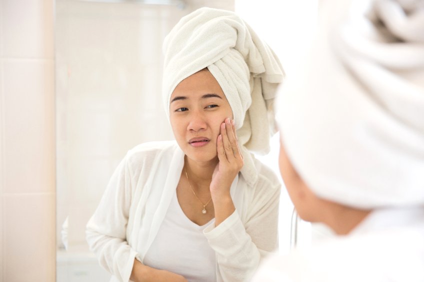 woman looking at her skin in mirror